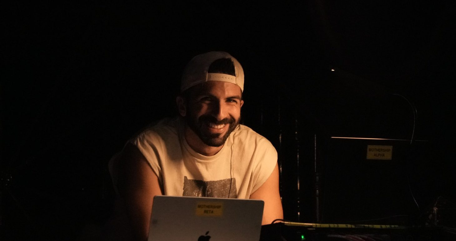 Founder Volkan Can Canbolat smiling behind a laptop in a dim studio