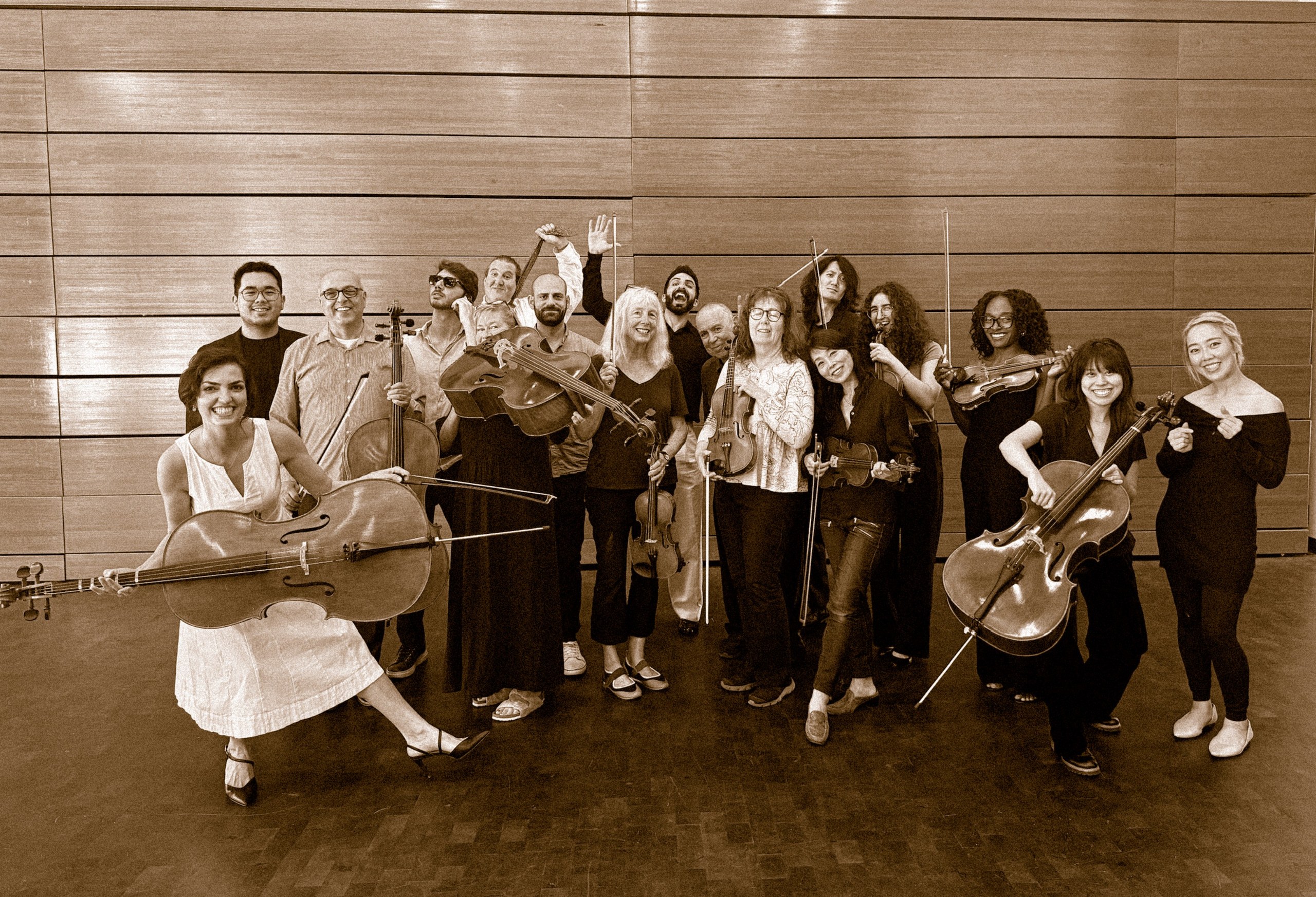Sepia photo of a smiling adult group class of string players holding violins and cellos
