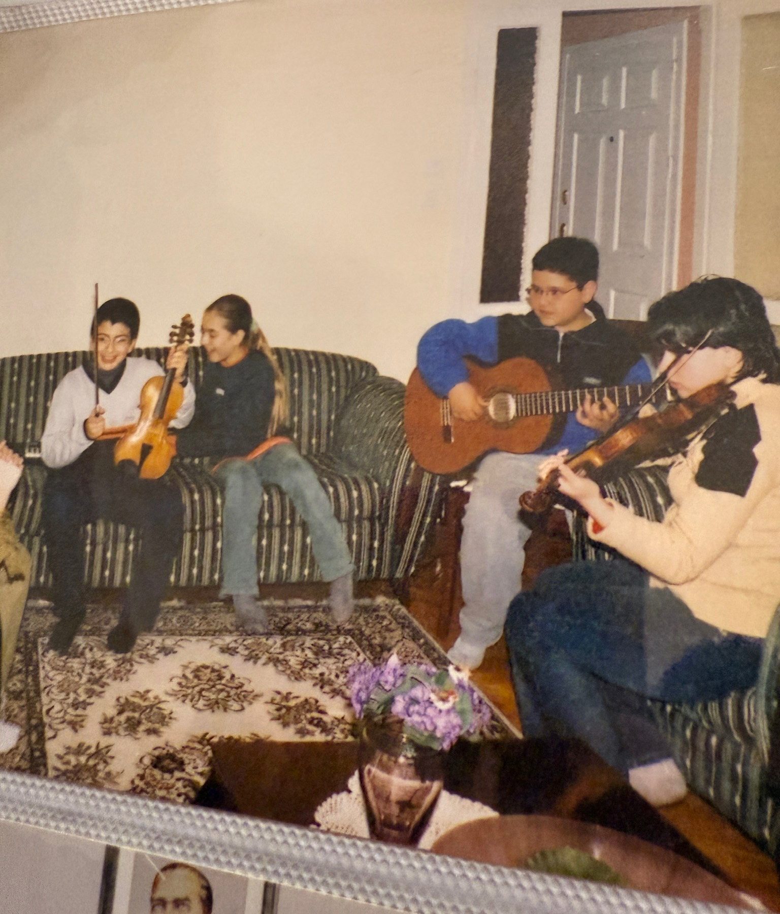 Vintage photo of kids playing guitars and violin together on a couch