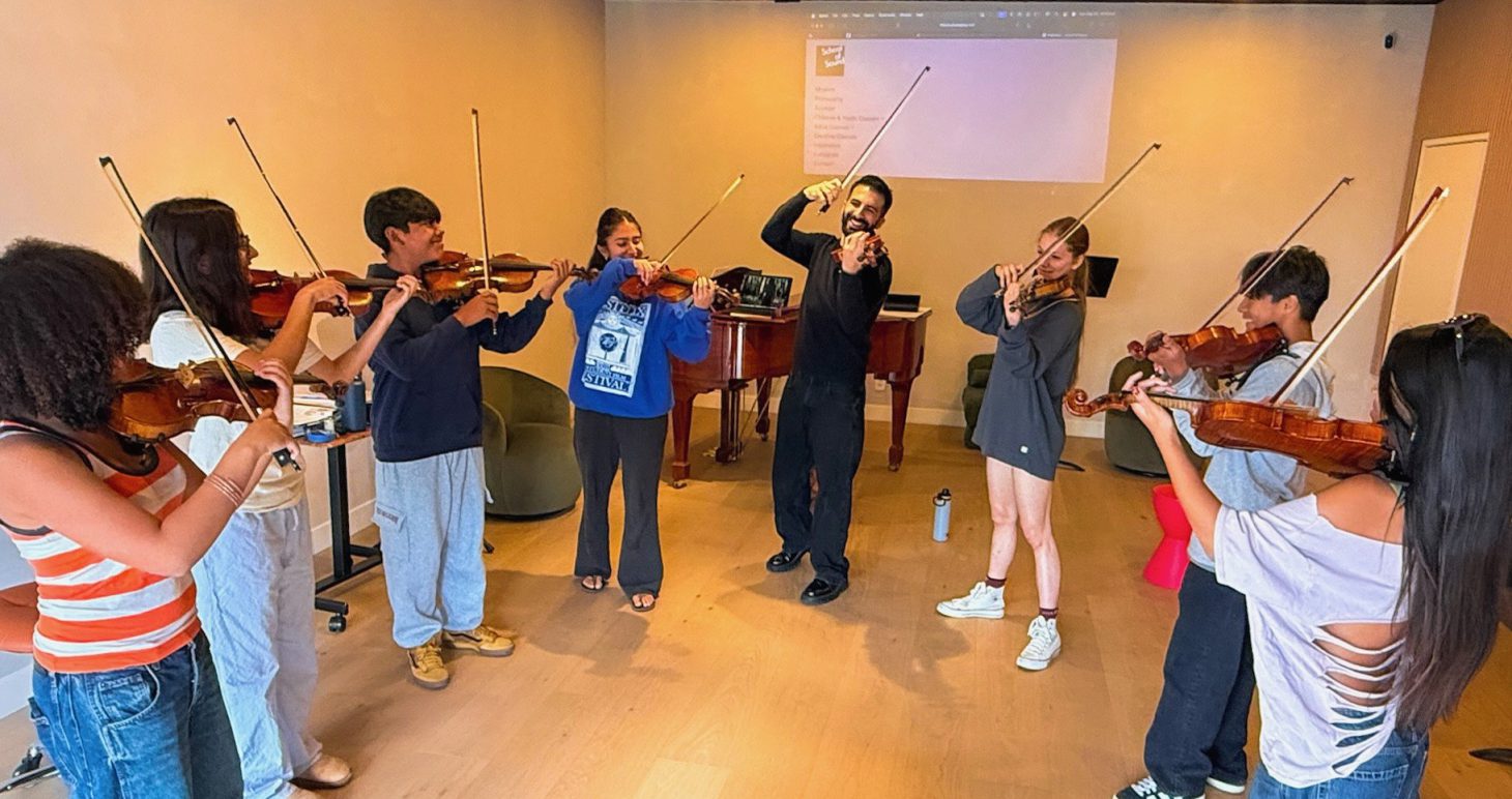 Young violinists standing in a circle, playing together with their teacher